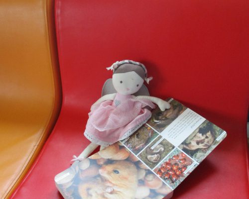 Puppe, die auf einem Stuhl im Kinderhaus Albatros liegt und ein Buch liest