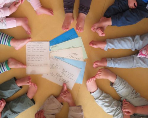Kinder des Kinderhaus Froschkönig, die in einem Kreis um Briefer herum sitzen